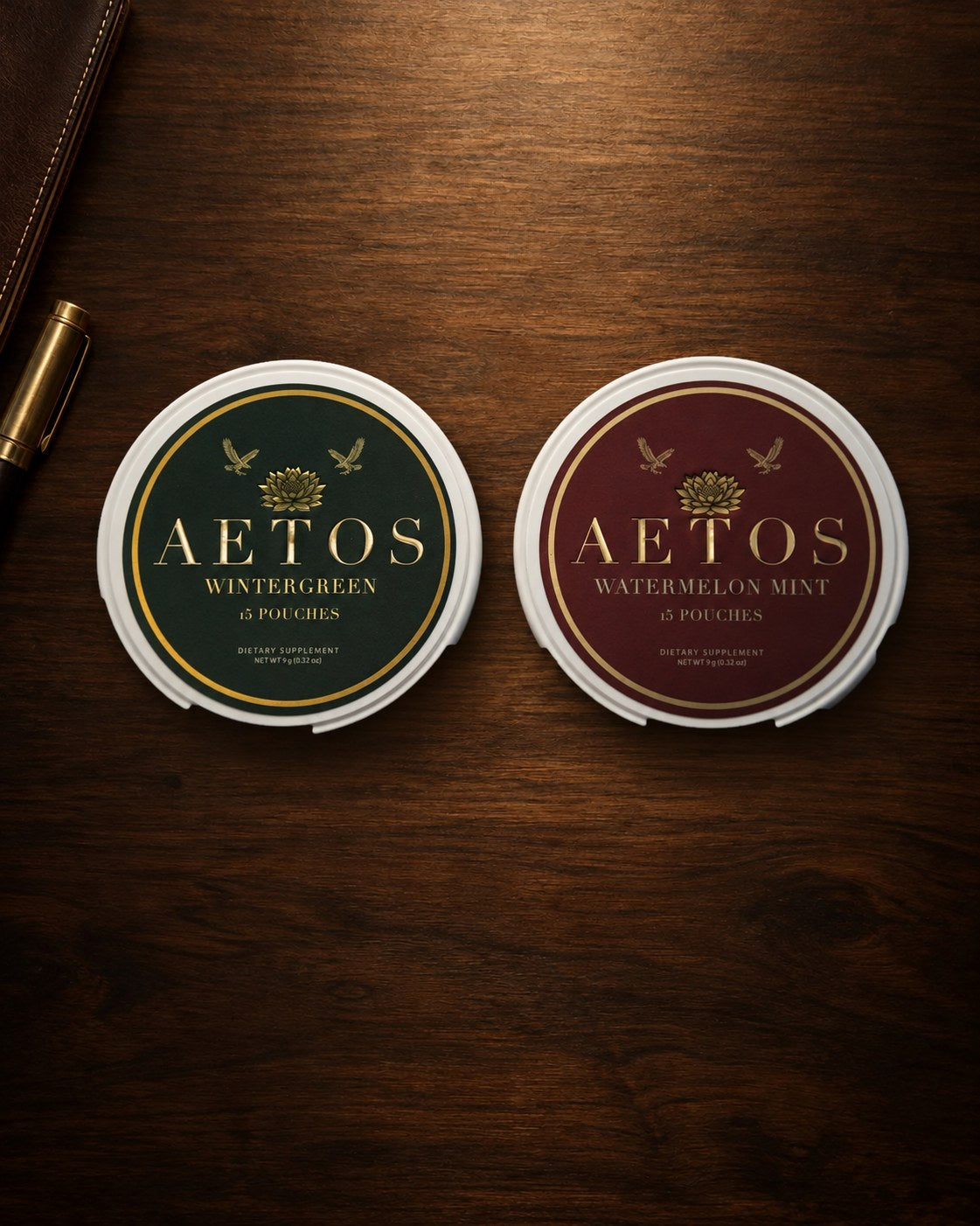 AETOS Wintergreen and Watermelon Mint cans on a walnut desk beside a pen